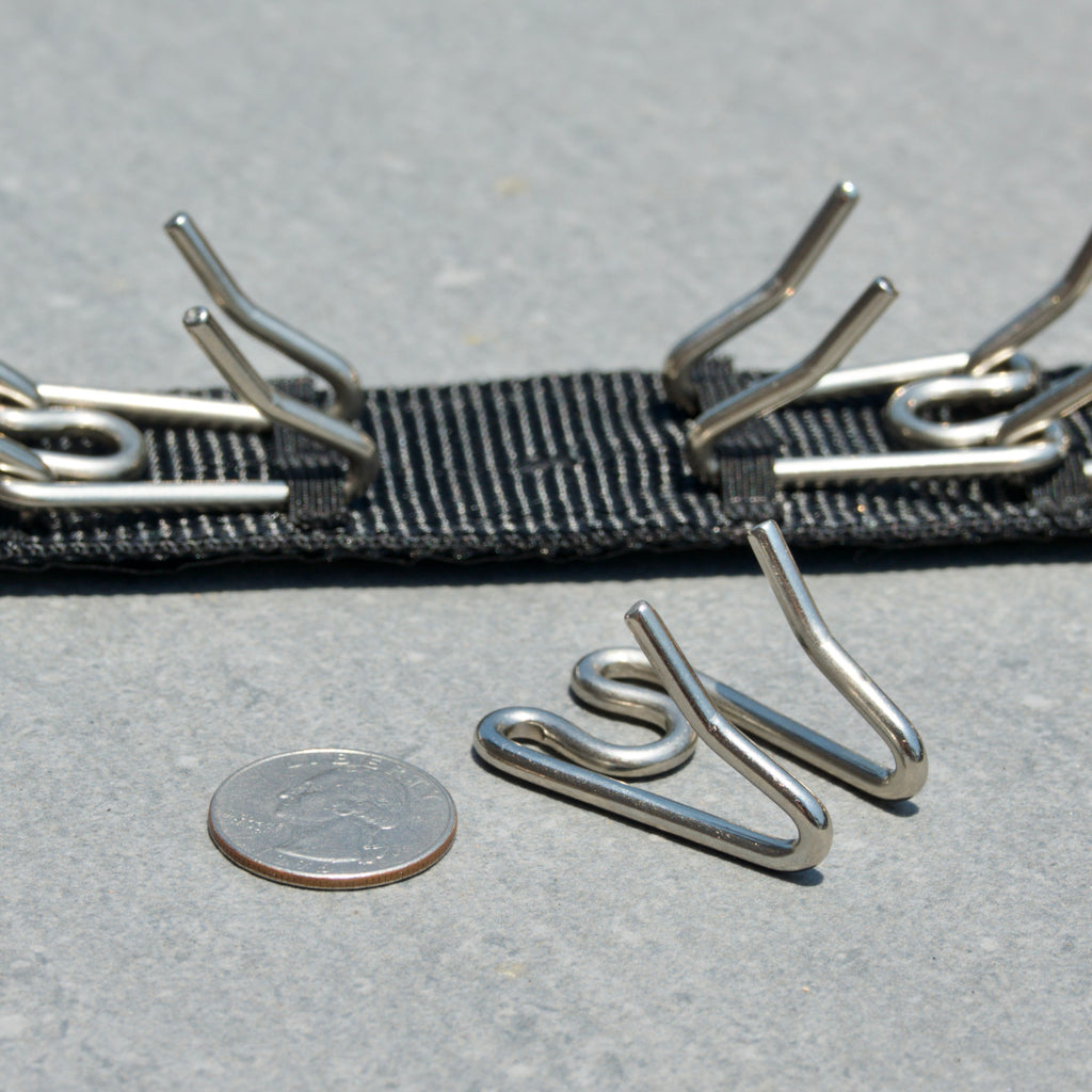 Dog training prong collar on a gray surface, next to a Quarter for scale of large prongs.