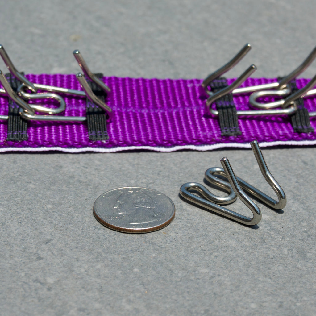 Dog training prong collar on a gray surface, next to a quarter for scale of medium prongs.
