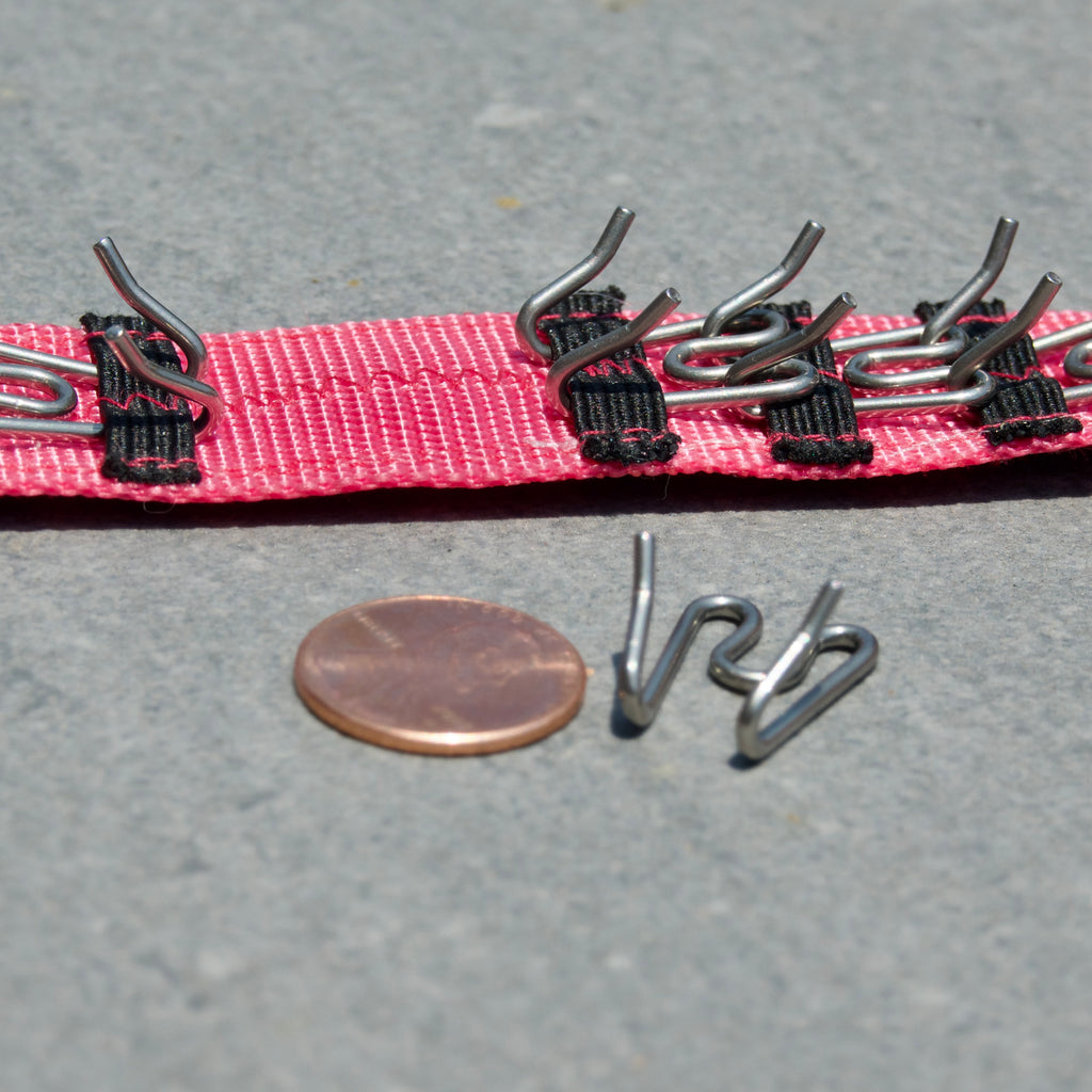 Dog training prong collar on a gray surface, next to a penny for scale of small prongs.